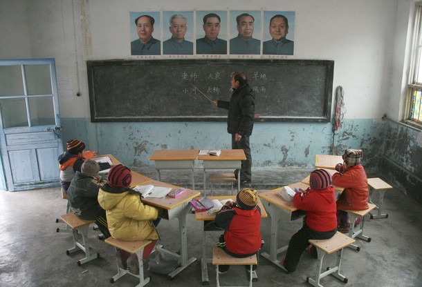 Pupils listen to the teacher under the portraits of China's former leaders at Gao'er Hope School located on the top of Xiaohuatan Mountain in Jinan