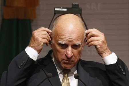 California Governor Jerry Brown adjusts his earpiece during a news conference at Memoria y Tolerancia museum in Mexico City